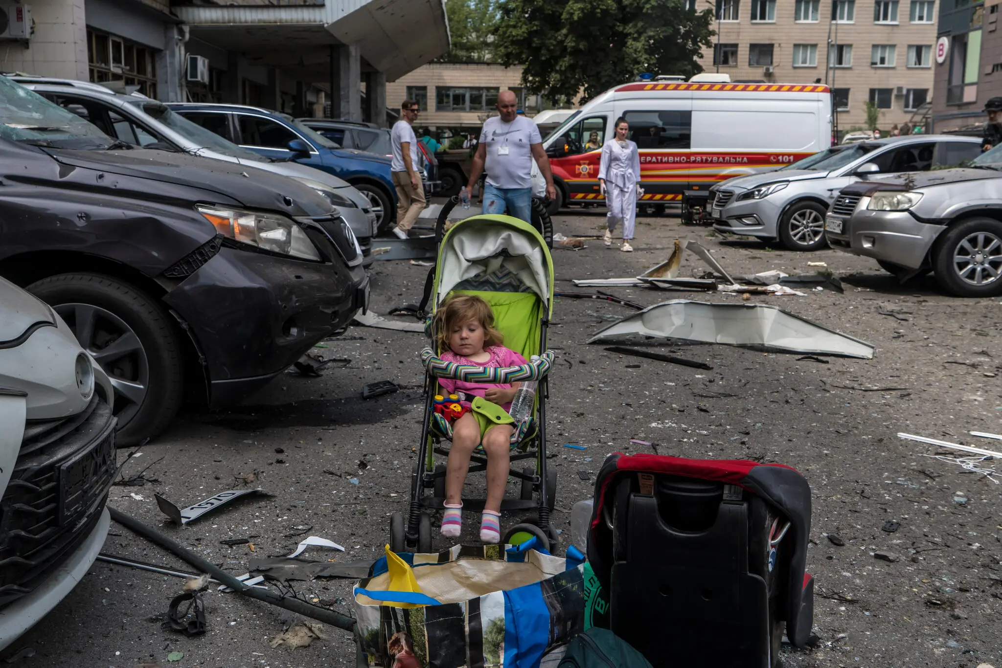 Дівчинка дрімає в колясці серед уламків після російського ракетного удару.